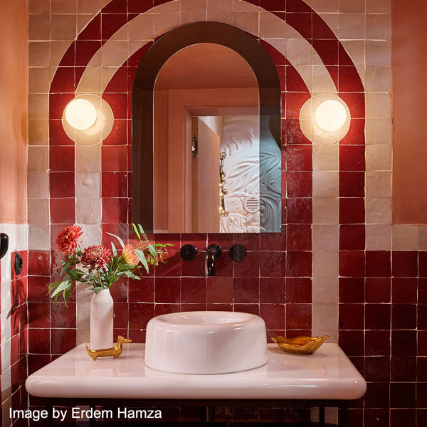 Crimson zellige and white wall tiles in an arch in a bathroom